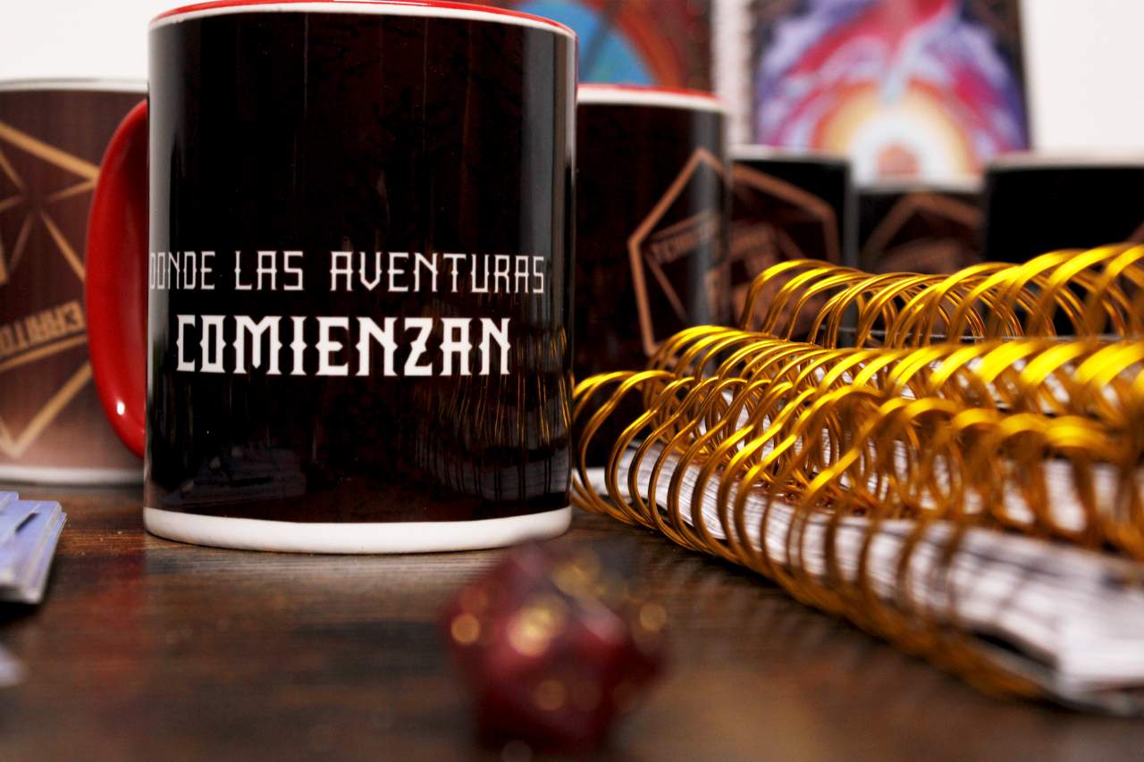 Tazas, d20 y libretas en una mesa.