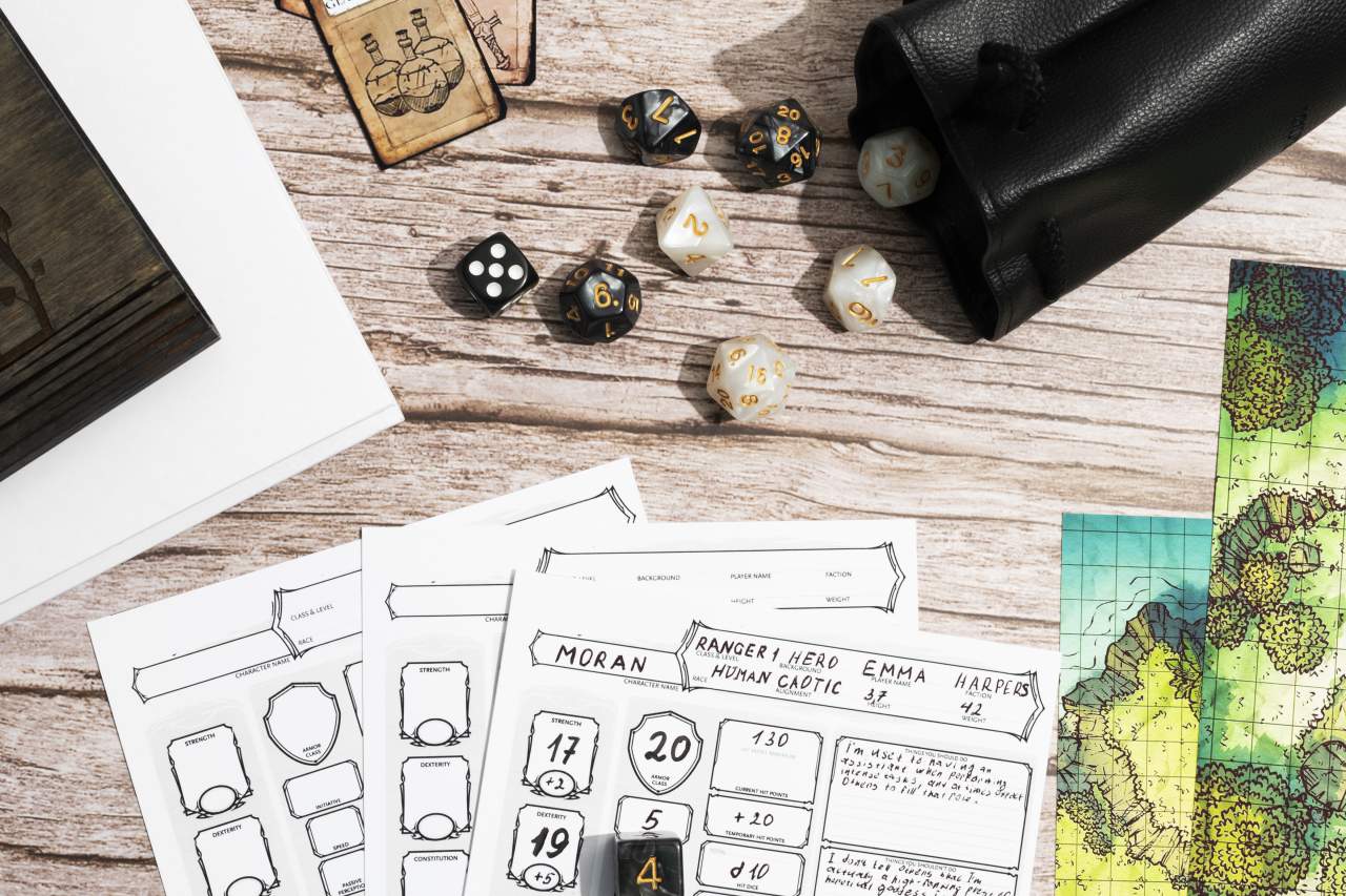 Hojas de personaje, dados, tarjetas y mapas de rol en una mesa de madera.